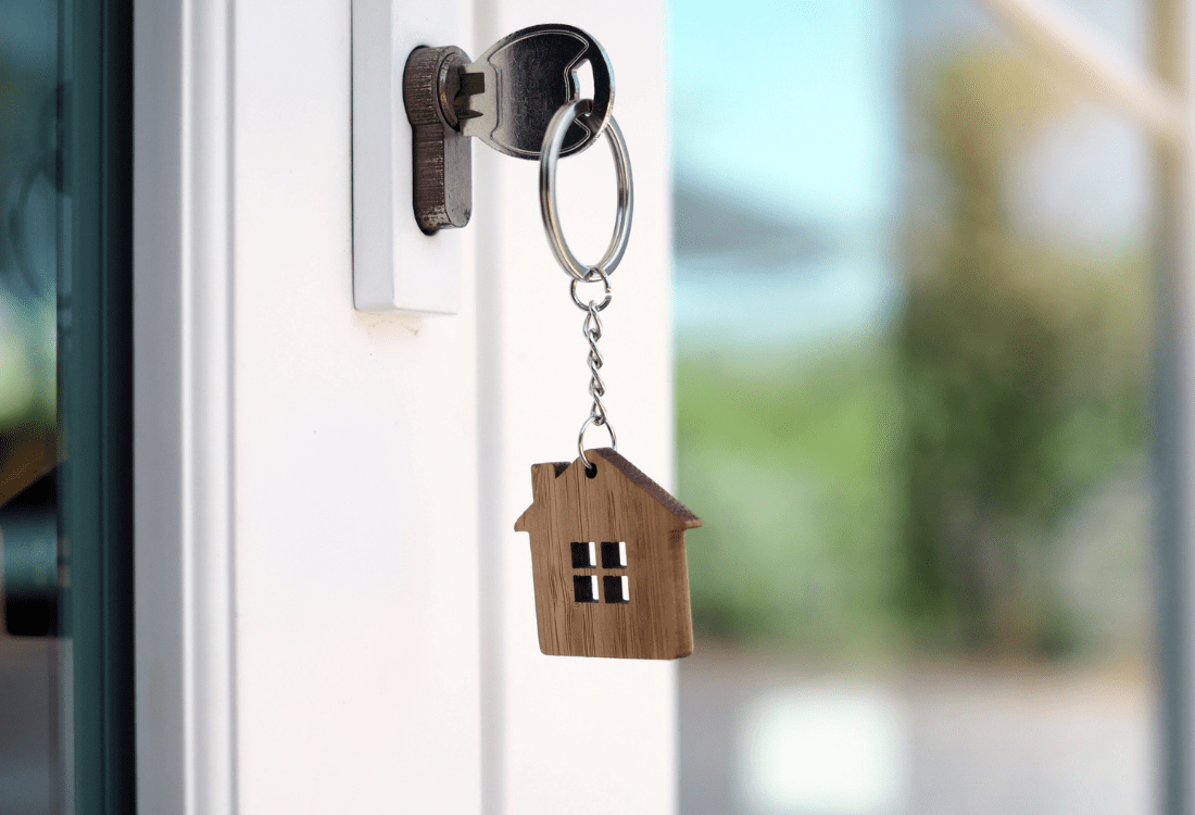 A key in the lock of a door with a key ring of a house showing that it is secure.  